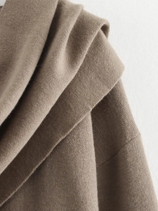 Detailed macro view of tan knit cardigan showing thick soft texture and layered collar craftsmanship