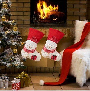 Detail of red and white knitted Christmas stockings with snowman designs by a fireplace