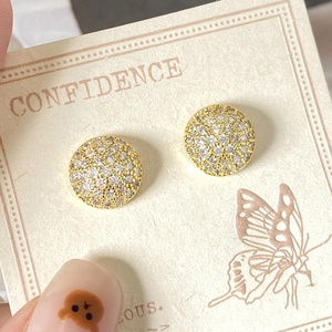 Close-up of gold-plated round stud earrings with shimmering pave-set cubic zirconia stones