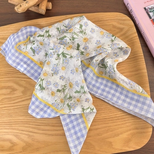 Close-up of cotton linen headscarf with daisy print and blue plaid on a wooden tray