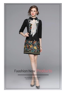 Detail of colorful floral embroidery and white chiffon bow on black midi dress