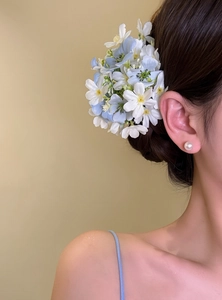 Close-up of model wearing light blue and white floral hair clip for vacation style.