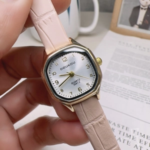 Detailed view of square gold watch with silver dial and pink leather strap