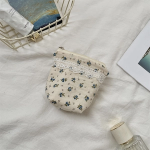 Detailed macro view of cream floral cosmetic bag with delicate blue prints and lace trim