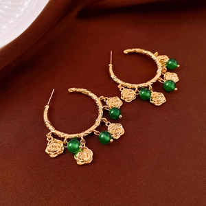Vintage bohemian gold hoop earrings with rose charms and green beads on velvet