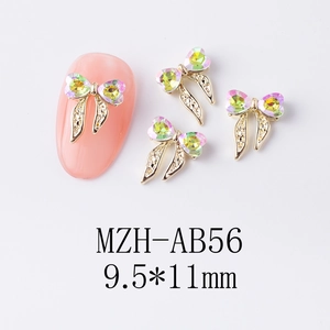 Détail du bijou d'ongle nœud doré 9,5x11mm avec strass cœur AB sur ongle rose modèle