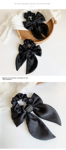 Close-up of two black satin bow hair scrunchies with Hand Made woven labels
