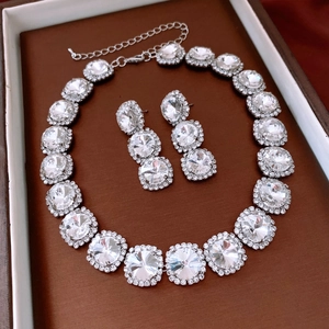 Macro view of crystal-encrusted round pendant necklace and earrings in jewelry box