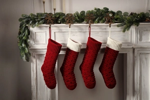Close-up of four red and white knitted Christmas stockings on a decorated fireplace