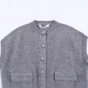 Gilet en maille gris moyen avec col rond, boutons centraux et deux grandes poches plaquées