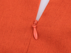 Detail view of the seamless invisible zipper on the orange woven fabric of the dress