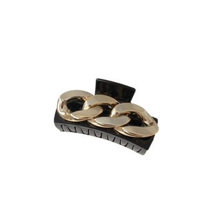 Minimalist black hair claw clip with elegant gold chain link accent on a clean background
