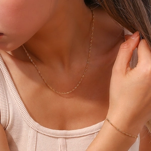 Dettaglio del set collana e bracciale a catena a onde dorate indossato dalla modella