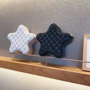Close-up of star-shaped quilted crossbody bags in black and white glossy patent leather