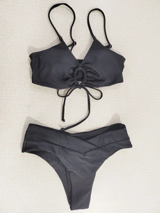 Flat lay of black bikini set featuring a V-neck halter top with ring detail and V-waist bottoms