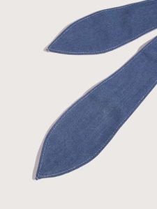 Macro detail of blue denim waist belt showing texture and white contrast stitching