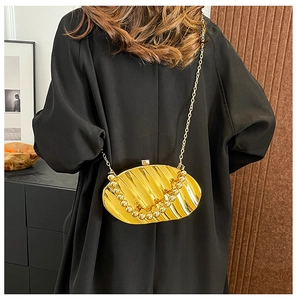 Gold acrylic leaf shell evening bag with vertical pleats and metallic chain on a model