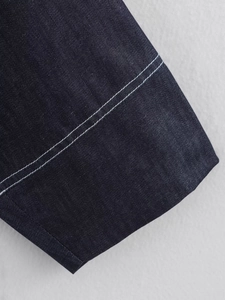 Close-up of dark blue denim jacket cuff featuring detailed double white stitching