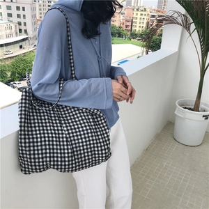 Classic black and white checkered canvas tote bag with shoulder strap shown on a model