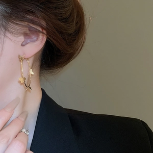 Close-up of elegant gold hoop earrings featuring delicate butterfly charms for women