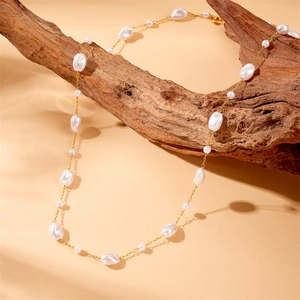 Baroque pearl necklace with gold stainless steel chain draped on a natural wooden branch