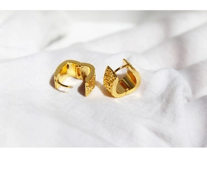 Detailed macro view of 24k gold-plated trapezoid earrings with hammered metal texture