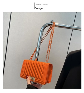 Detail of vibrant orange quilted crossbody bag with gold chain and twist-lock clasp