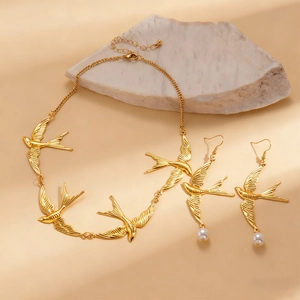 Details des goldenen Schwalben-Schmucksets mit Vogelkette und Perlenohrringen