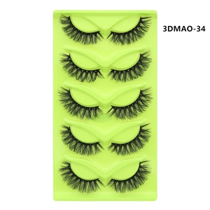 Detailed view of 5 pairs of thick black cat-eye false eyelashes on a green tray
