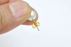 Macro view of 18K gold plated butterfly earring back and silver pin with white pearl detail