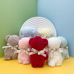 Macro detail of assorted colorful coral fleece bear-shaped towels with pearl ribbons
