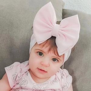 Close-up of pink oversized double-layer bow headband on baby in floral outfit