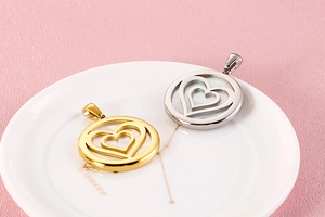 Detail view of gold and silver heart pendants with mother of pearl on a ceramic tray