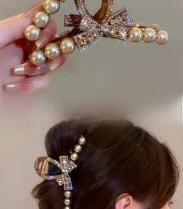 Detail of large brown hair claw with premium pearls and sparkling rhinestone bow design