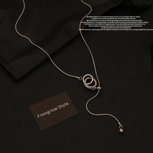 Close-up of silver snake chain necklace with sparkling intertwined double ring pendant