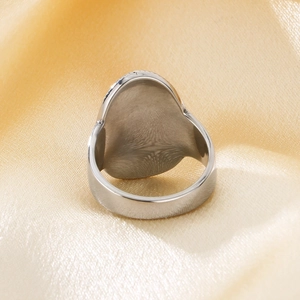 Detail of wide polished stainless steel oval ring on champagne silk background