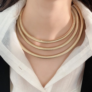 Detail of three-layer gold snake chain necklace on model with chic layered design
