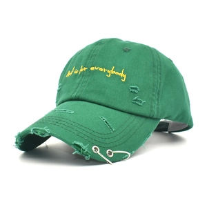 Close-up of distressed green baseball cap with yellow embroidery and metal rings
