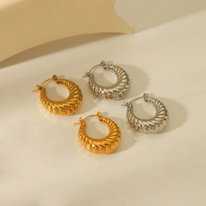 Close-up of 18K gold and silver hollow croissant hoop earrings with spiral texture