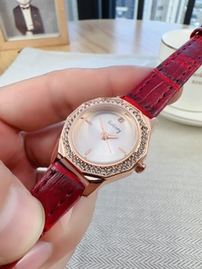 Detail of a red leather strap watch with rose gold diamond bezel on a woman's wrist
