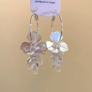 Detailed shot of gold plated floral earrings with shimmering crystal pendants and hoop
