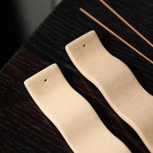 Support d'encens minimaliste en céramique au design ondulé sur une table en bois