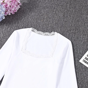 Detailed view of white long-sleeve top featuring intricate lace trim and square neckline