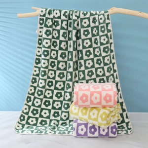 Soft coral fleece towel set with floral checkerboard pattern hanging on wooden stand