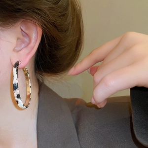 Close-up of large leopard print hoop earrings with gold inner lining on model
