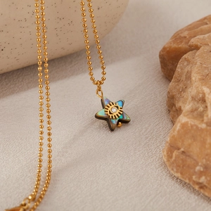 Detailed shot of star pendant with iridescent abalone shell and golden eye motif