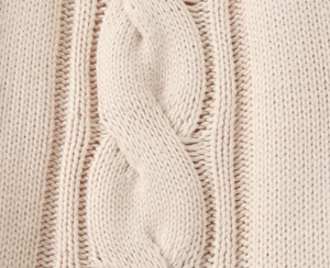 Macro detail of high-quality beige cable knit texture on a soft knitted dress