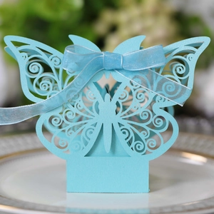 Close-up of light blue laser-cut butterfly candy box with a ribbon on a white plate