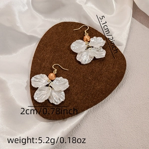 Detailed dimensions of white petal and gold pearl earrings on brown velvet background