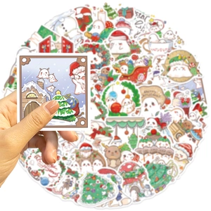 Close-up of hand holding colorful Christmas ghost stickers with Santa and reindeer motifs